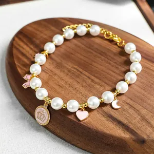 Détail macro d'un collier en perles pour animaux avec breloques couronne rose et or