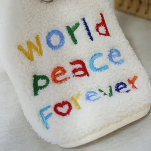 Dettaglio del ricamo colorato world peace forever su morbido pile sherpa bianco per animali