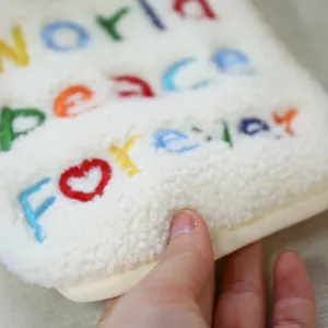 Dettaglio in morbida lana d'agnello con ricamo colorato World Peace Forever