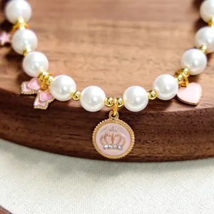 Détail du collier de perles pour animaux avec nœud rose et pendentif couronne en cristal
