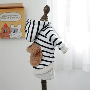 Striped pet hoodie with plush bear paw pocket on a wooden model for small dogs