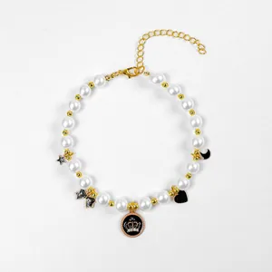 Détail du collier pour animaux avec perles blanches, boules dorées et charms noirs