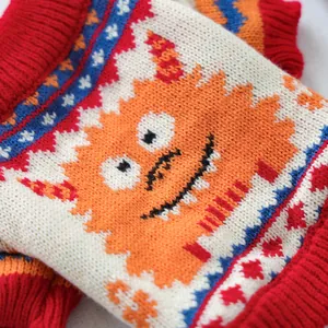Close-up of knit pet sweater featuring orange monster and Nordic geometric patterns
