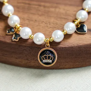 Détail macro d'un collier luxe pour animaux avec perles blanches et pendentifs couronne noirs