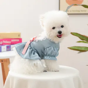 Vestito blu per cani con fiocco rosa e pizzo su un cane Bichon Frise bianco