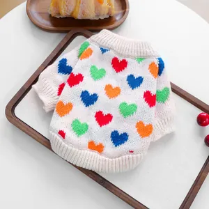 Detailed knit of white pet sweater with colorful heart patterns and ribbed cuffs