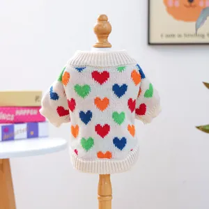 Detail of pet knit sweater with colorful jacquard hearts on a cream ribbed background