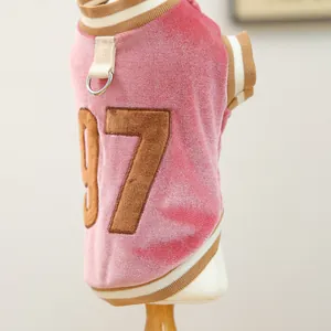 Detail of pink velvet pet vest showing brown number 87 embroidery and metal D-ring attachment