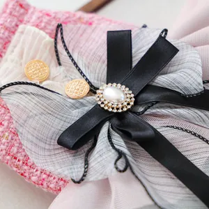 Dettaglio macro di un accessorio vintage per animali con fiocco di raso, perla e strass
