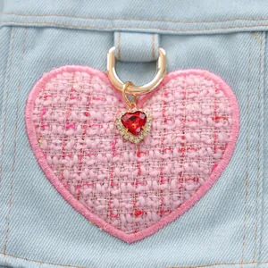 Detalle de parche de corazón en tweed con gema roja en chaqueta vaquera de perro