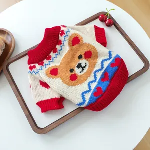 Close-up of a knit pet sweater with a brown bear pattern and red ribbed collar and cuffs