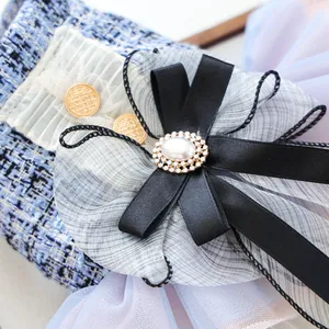 Dettaglio di fiocco in tulle blu con perla e strass su tessuto in tweed raffinato