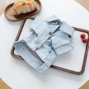 Detalle de camisa vaquera azul claro para mascotas con botones metálicos en madera