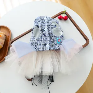 Dettaglio della trama in tweed, bottoni blu e tulle a strati su un abito da principessa