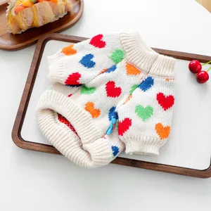 Detalle de los patrones de corazones coloridos y dobladillo acanalado en el suéter blanco
