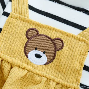 Detail of yellow corduroy pet overalls with brown bear embroidery and striped lining