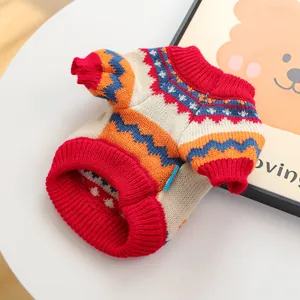 Detail of knit pet sweater featuring orange geometric wave pattern and blue fabric label