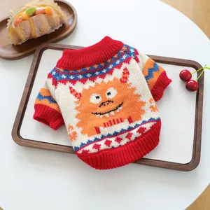 Detail of knitted pet sweater showing orange monster jacquard and red ribbed cuffs