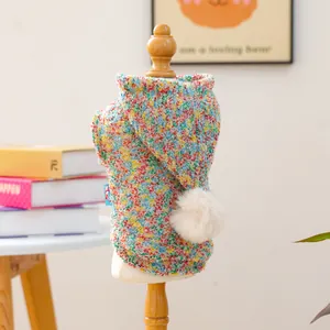 Detail of colorful knitted pet hoodie with a white pompom on a display mannequin