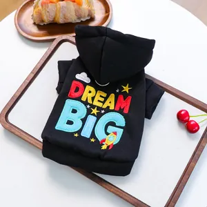 Detail of black pet hoodie with Dream Big embroidery and rocket patterns on wood