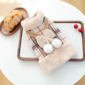 Close-up of plaid pet vest with faux fur collar, knitted bow, and plush pom-pom details