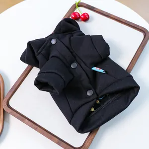 Detail view of black pet hoodie with snap buttons and folded cuffs on a wooden tray