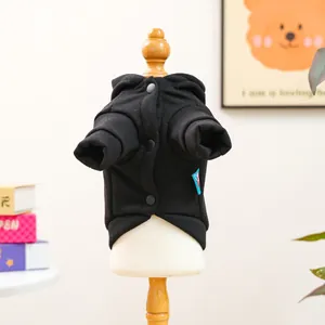 Detail of black pet hoodie with front buttons and brand label on a wooden stand