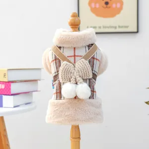 Close-up of winter pet vest with plaid pattern, decorative bow and white pom-poms
