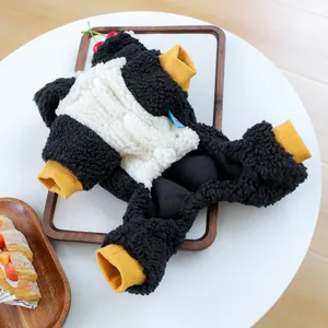 Detalle de mono de felpa para mascota estilo pingüino con puños elásticos amarillos