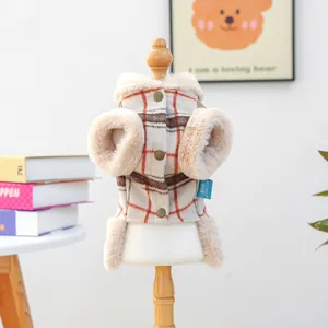 Detail of a beige plaid pet vest with plush trim and bronze buttons on a wooden stand