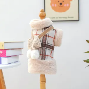 Detail of plaid pet vest featuring plush faux fur trim, knit bow and soft white pom-poms
