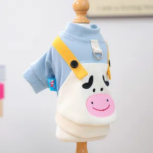 Detalle del suéter para mascota con diseño de vaca rosa y tirantes amarillos en tejido azul