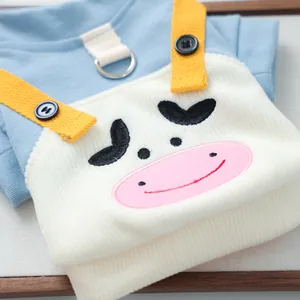Detalle del chaleco de punto azul para mascotas con bordado de vaca y correas amarillas