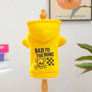 Détail d'un sweat à capuche jaune pour animaux avec imprimé BAD TO THE BONE et crâne