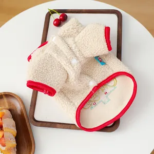 Detail of pet sherpa fleece vest with red trim and festive embroidery on wood tray
