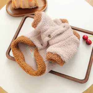 Detailansicht der flauschigen Haustier-Vliesweste mit Druckknöpfen auf Holztablett