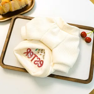 Close-up of cream ribbed knit pet hoodie with red Easter embroidery and rabbit pattern
