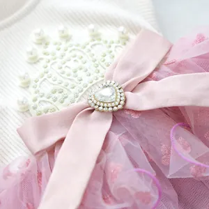 Close-up of pink pet dress featuring lace crown, satin bow, and heart rhinestone detail