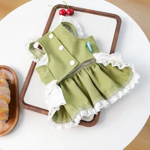 Détail d'une robe verte pour animaux avec dentelle blanche et boutons sur plateau