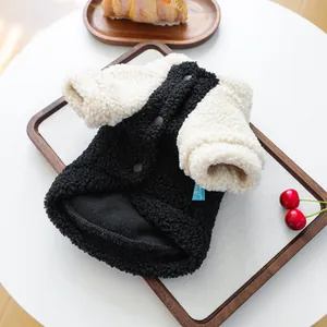 Close-up of cozy black sherpa pet vest with contrast cuffs on a wooden tray