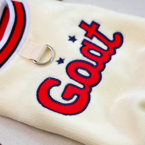 Detail of soft ivory corduroy pet vest with GOAT embroidery and metal D-ring attachment