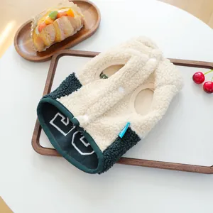 Detailansicht einer warmen Sherpa-Fleece Haustierweste mit Knöpfen auf Holztablett