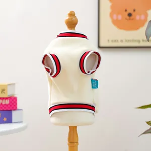 Close-up of cream pet knit vest with red and black striped ribbing and brand tag