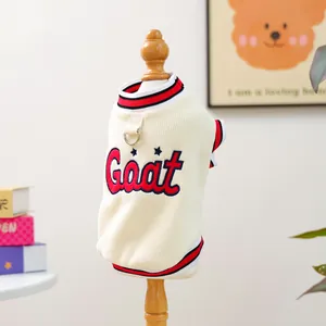 Detail of cream pet vest with red and black striped trim and D-ring on textured fabric