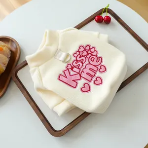 Detailed close-up of cream knit pet sweater with pink Kiss Me embroidery and metal D-ring