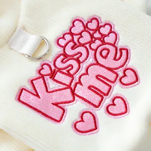 Detail of pink sequin KISS ME heart embroidery and D-ring on soft ribbed pet sweater