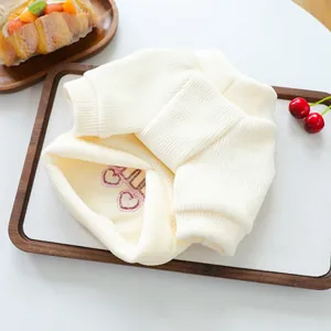 Detail of cream knit pet sweater featuring pink heart embroidery and ribbed cuffs