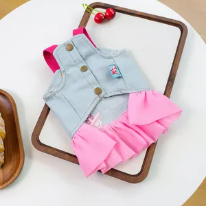 Detail of pink ruffled denim pet dress with gold buttons on a wooden tray background