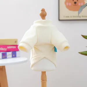 Close-up of cream ribbed knit pet sweater with blue brand label on wooden hanger