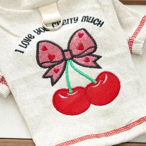 Detail of cherry embroidery with pink sequins and metal D-ring on pet base shirt